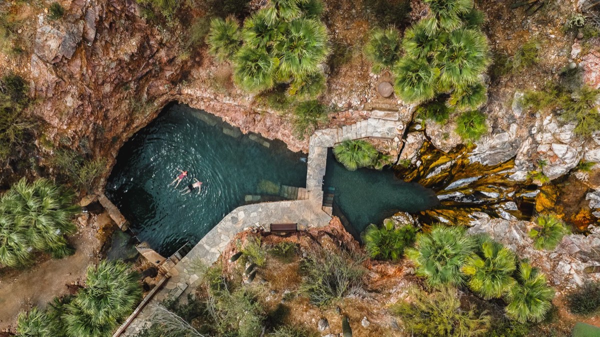 Aerial view of Castle Hot Springs' stone-edged spring pools among palms and rock