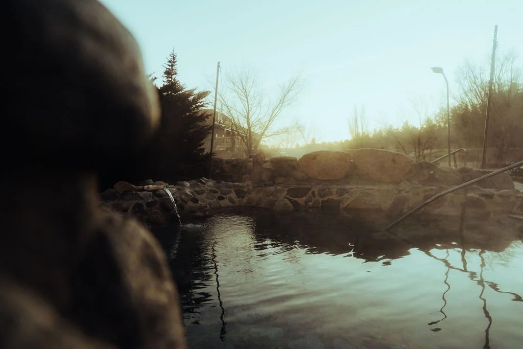Stone-lined Cottonwood Hot Springs soaking pool at dusk, trees reflected in the water
