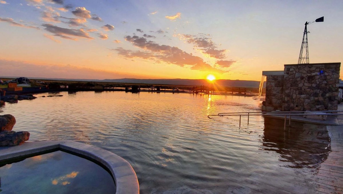 Crane Hot Springs' large pond at sunset with stone fountain tower and small soaking tub
