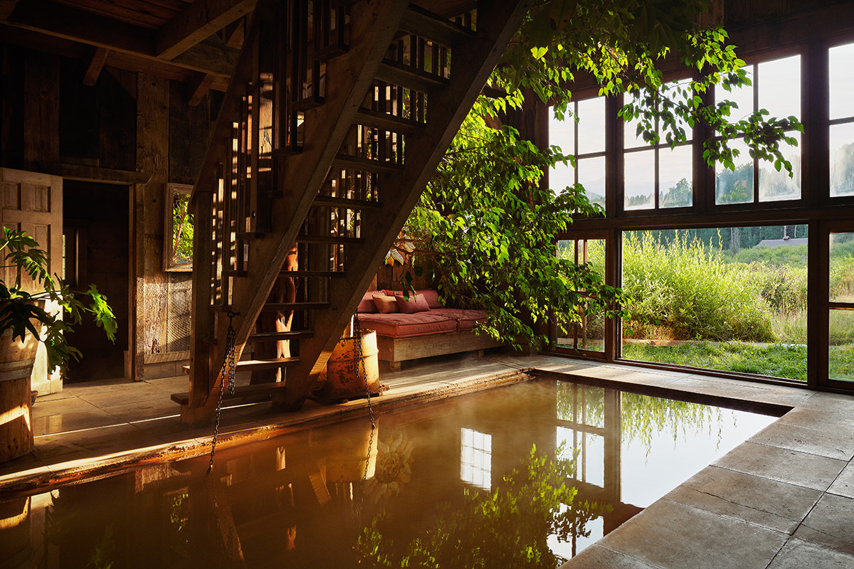 Indoor pool in Dunton's historic log bathhouse, windows opening onto green meadow