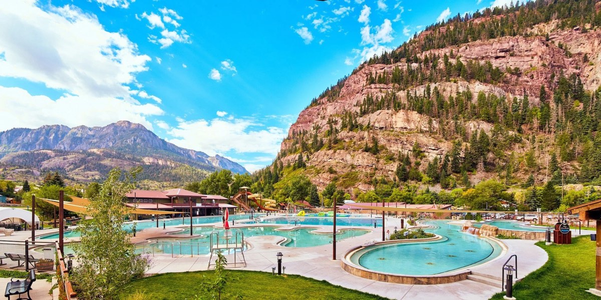 Ouray's outdoor hot springs pool complex with curving soaking pools beneath red cliffs and mountains