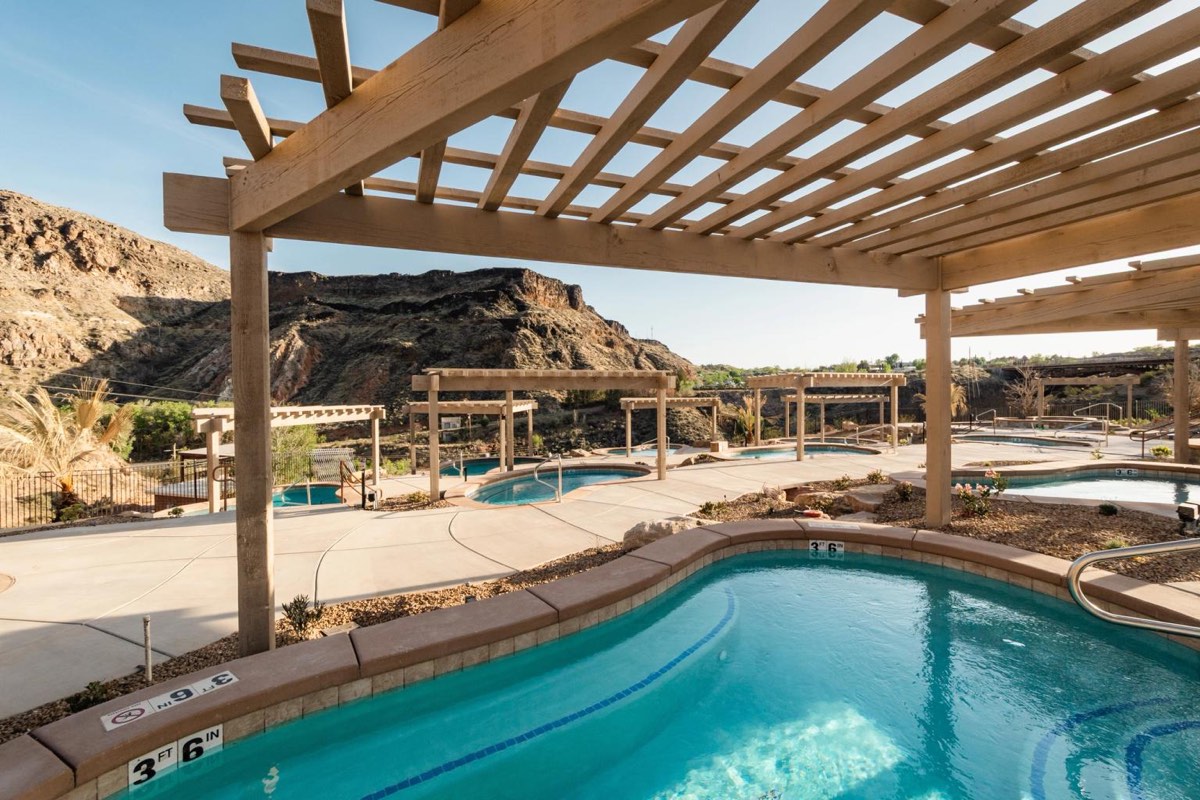 Turquoise soaking pools under wooden pergolas, rocky canyon walls behind
